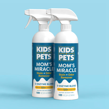 Two white spray bottles labeled "Kids 'N' Pets Mom's Miracle Stain + Odor Remover" with trigger sprayers on a light blue back